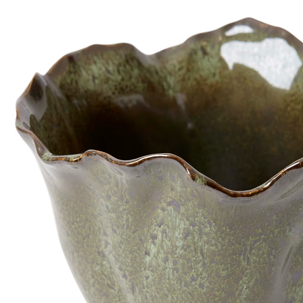 Close-up of a ceramic vessel with a scalloped, wavy rim and a textured, speckled glaze in olive green and brown tones, set against a plain white background.