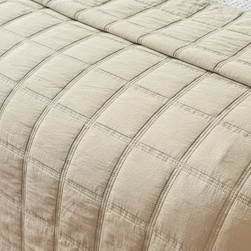 Beige quilted comforter on a bed with pillows