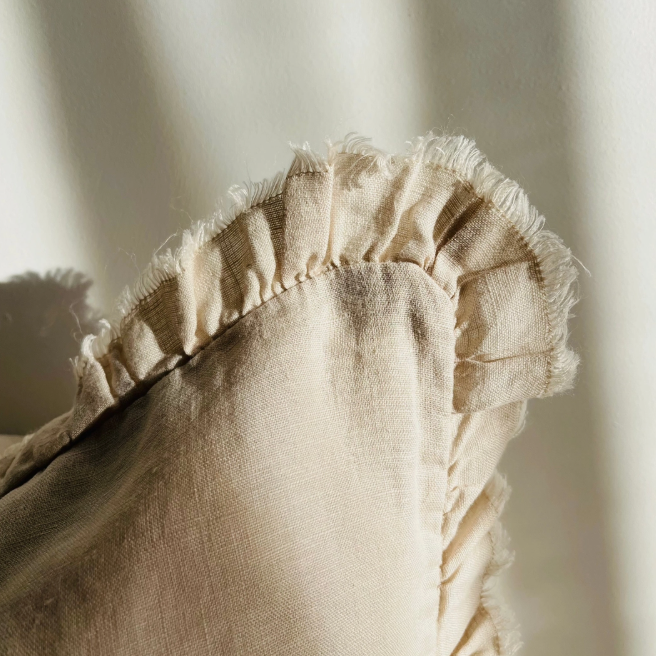 Close-up of a beige fabric pillow with ruffled edge