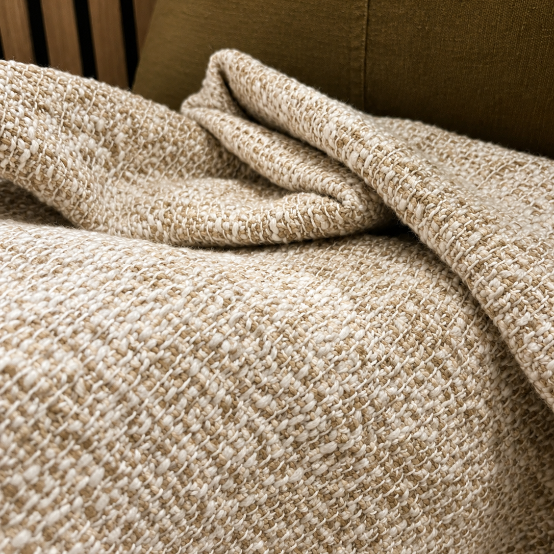 Textured beige blanket draped over a brown sofa